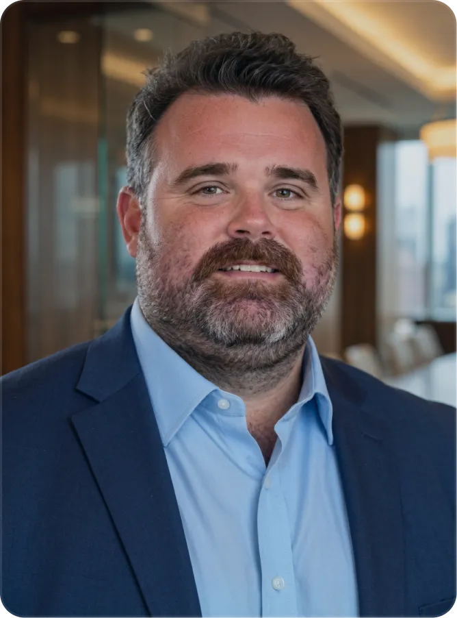 Portrait of a bearded man in a blue suit jacket and light blue shirt in an office setting.